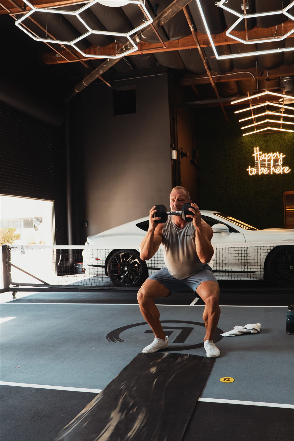 A member holding a demanding dumbbell squat during a shared training session