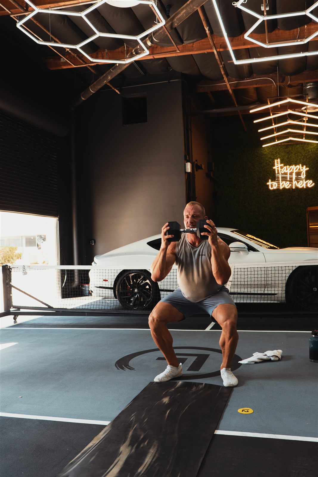 A member of The Standard practicing a dumbbell squat during a training session